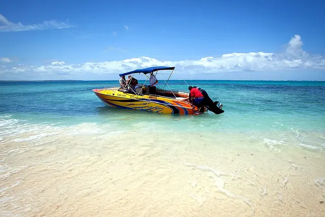Yellow speedboat pulled up on a white-sand beach