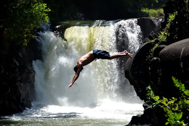 A guest diving into the pool below the waterfall